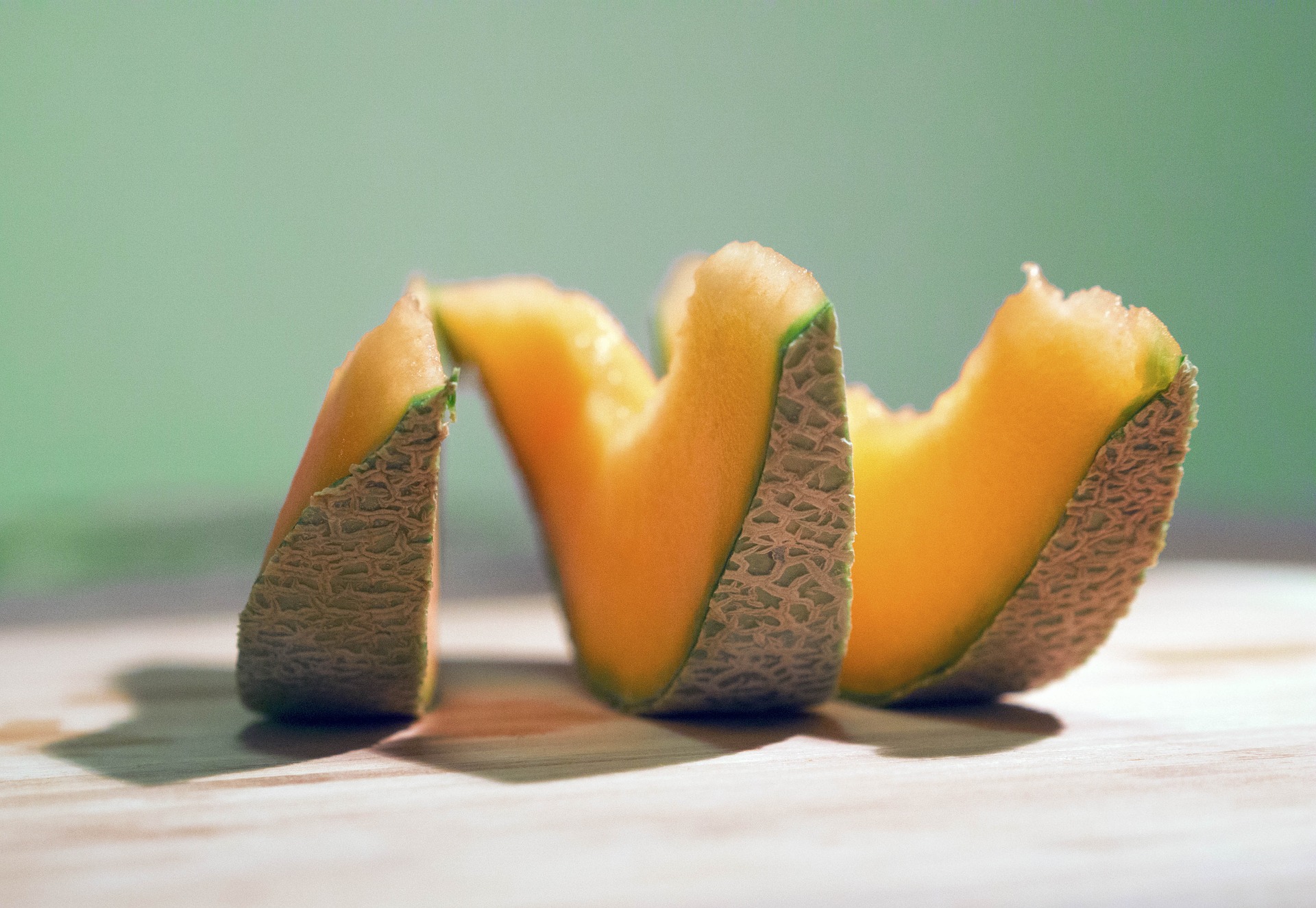 sliced cantaloupe melon with rind on a white table